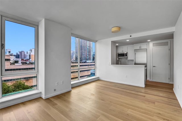 635 W 42nd St Unit 7A, New York Manhattan, NY 10036 - unfurnished living room featuring a view of skyline, light wood-type flooring, and recessed lighting