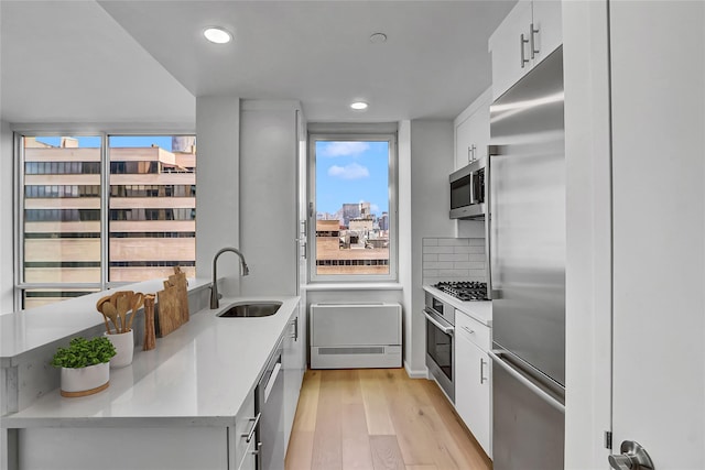 635 W 42nd St Unit 7A, New York Manhattan, NY 10036 - kitchen with appliances with stainless steel finishes, light wood-type flooring, white cabinetry, light countertops, and recessed lighting