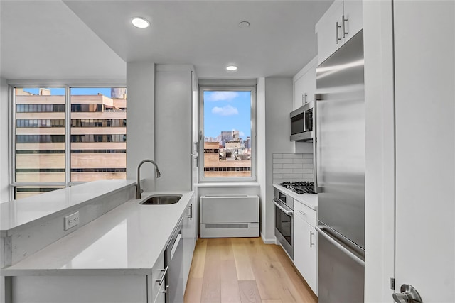 635 W 42nd St Unit 7A, New York Manhattan, NY 10036 - kitchen with stainless steel appliances, light wood finished floors, white cabinetry, light countertops, and recessed lighting