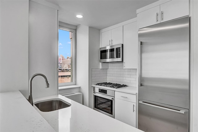 635 W 42nd St Unit 7A, New York Manhattan, NY 10036 - kitchen with stainless steel appliances, decorative backsplash, white cabinets, and recessed lighting