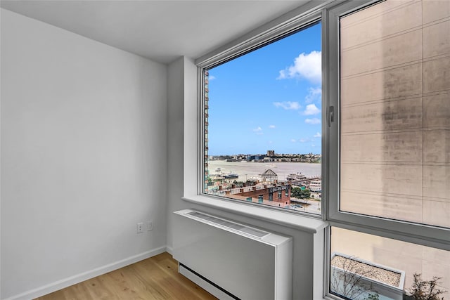 635 W 42nd St Unit 7A, New York Manhattan, NY 10036 - spare room featuring wood finished floors, radiator heating unit, and a view of city