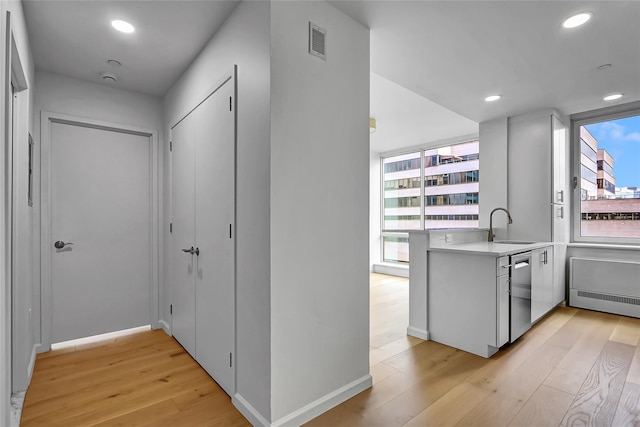 635 W 42nd St Unit 7A, New York Manhattan, NY 10036 - kitchen with light wood-type flooring, a peninsula, light countertops, stainless steel dishwasher, and recessed lighting