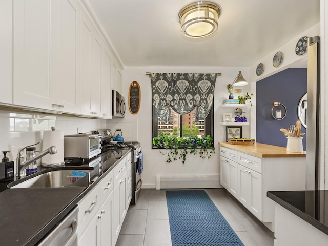 666 Pelham Rd Unit 3N, New Rochelle, NY 10805 - kitchen featuring stainless steel appliances, decorative backsplash, white cabinetry, butcher block counters, and light tile patterned flooring