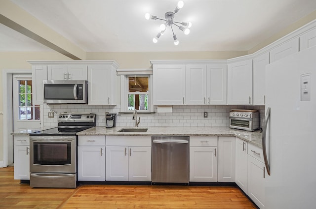 52 Mc Cue Ln, Babylon, NY 11702 - kitchen with appliances with stainless steel finishes, light wood-style flooring, white cabinets, backsplash, and light stone counters