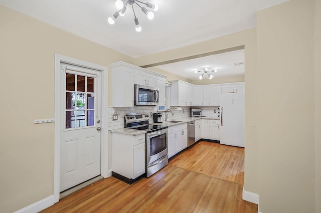52 Mc Cue Ln, Babylon, NY 11702 - kitchen featuring stainless steel appliances, tasteful backsplash, a chandelier, light wood-style floors, and white cabinetry