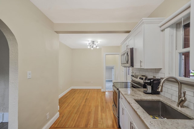 52 Mc Cue Ln, Babylon, NY 11702 - kitchen featuring stainless steel appliances, arched walkways, tasteful backsplash, white cabinets, and light stone countertops