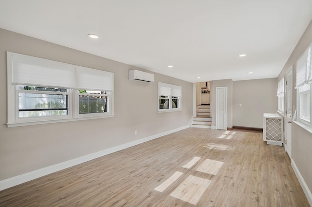 52 Mc Cue Ln, Babylon, NY 11702 - empty room with an AC wall unit, light wood-style flooring, stairway, and recessed lighting