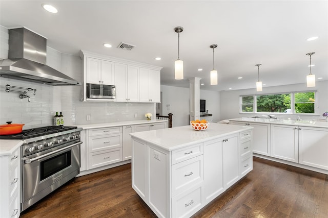 130 Carthage Rd, Scarsdale, NY 10583 - kitchen featuring stainless steel appliances, wall chimney range hood, backsplash, light countertops, and decorative columns