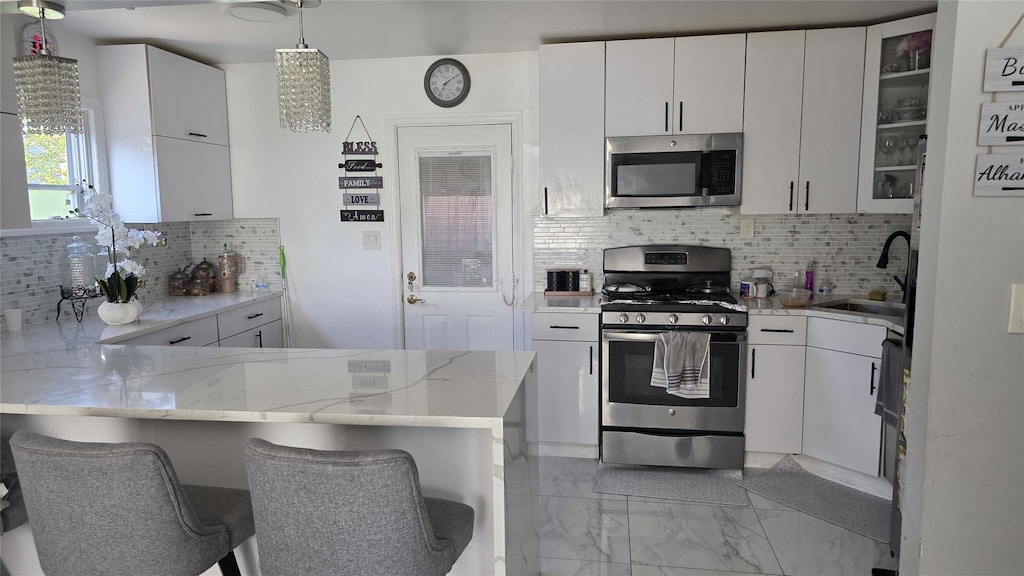 311 Travis Ave, Elmont, NY 11003 - kitchen featuring appliances with stainless steel finishes, light marble finish floors, a peninsula, and backsplash