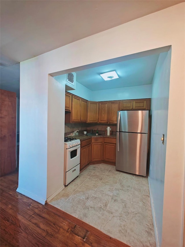 41-31 51st St Unit 6M, Woodside, NY 11377 - kitchen featuring freestanding refrigerator, gas range gas stove, dark countertops, and brown cabinets