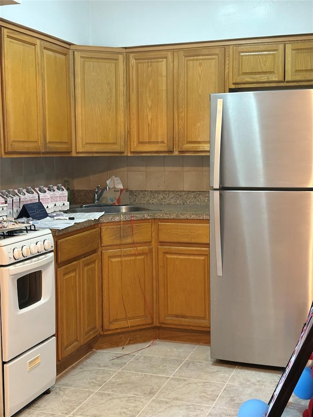 41-31 51st St Unit 6M, Woodside, NY 11377 - kitchen with freestanding refrigerator, white gas stove, brown cabinetry, light tile patterned floors, and dark countertops