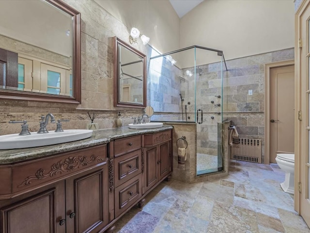 2000 Lake End Rd, Merrick, NY 11566 - bathroom with radiator heating unit, tile walls, double vanity, a stall shower, and stone finish flooring