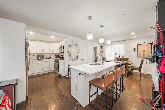 1098 Rte 311, Patterson, NY 12563 - kitchen featuring appliances with stainless steel finishes, dark wood-style flooring, white cabinetry, a kitchen bar, and an island with sink