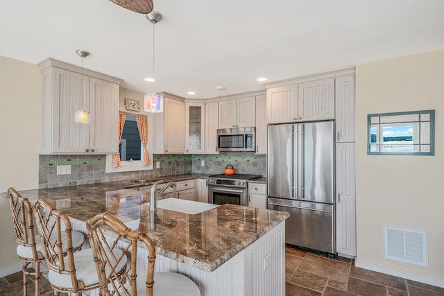 75 W Shore Rd Unit 4, Port Washington, NY 11050 - kitchen featuring stainless steel appliances, a peninsula, decorative backsplash, a kitchen bar, and glass insert cabinets