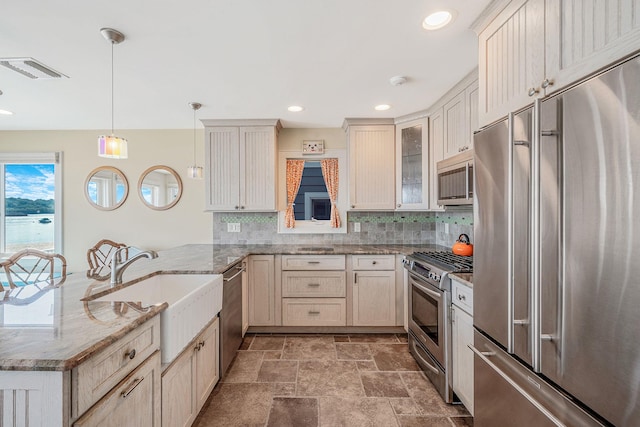 75 W Shore Rd Unit 4, Port Washington, NY 11050 - kitchen with stainless steel appliances, a peninsula, tasteful backsplash, hanging light fixtures, and light stone finish floors