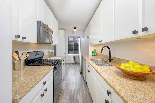 914 Wynnewood Rd Unit 3R, Pelham, NY 10803 - kitchen with appliances with stainless steel finishes, radiator, light wood-style flooring, backsplash, and white cabinetry