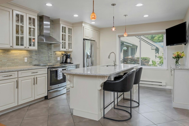 623 Heritage Hls Unit B, Somers, NY 10589 - kitchen with appliances with stainless steel finishes, wall chimney exhaust hood, a baseboard heating unit, backsplash, and light stone countertops