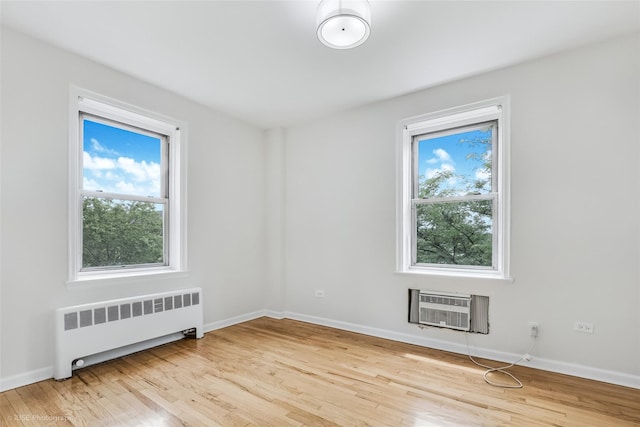 48-55 43rd St Unit 4H, Woodside, NY 11377 - empty room with radiator, healthy amount of natural light, an AC wall unit, and wood finished floors