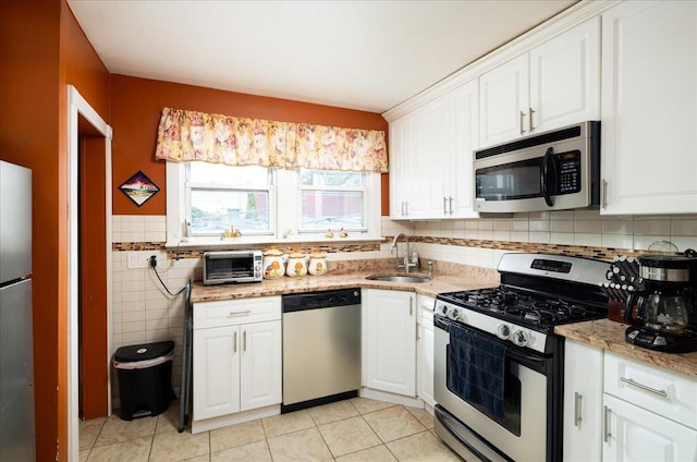 10719 Sutter Ave, Ozone Park, NY 11417 - kitchen with stainless steel appliances, white cabinets, light tile patterned floors, tile walls, and light stone countertops