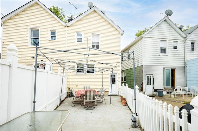10719 Sutter Ave, Ozone Park, NY 11417 - rear view of house featuring outdoor dining area, a patio, and a fenced backyard