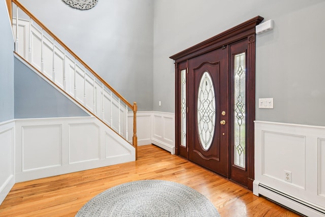 5 Aspen Cir, Saint James, NY 11780 - entrance foyer with a baseboard radiator, a decorative wall, wainscoting, light wood-style flooring, and stairs