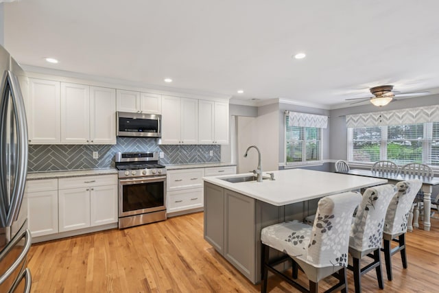 5 Aspen Cir, Saint James, NY 11780 - kitchen featuring appliances with stainless steel finishes, a kitchen breakfast bar, white cabinetry, decorative backsplash, and light countertops