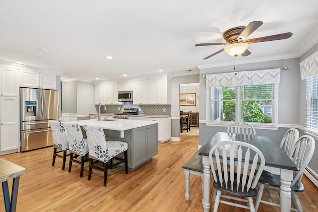 5 Aspen Cir, Saint James, NY 11780 - kitchen featuring appliances with stainless steel finishes, ornamental molding, white cabinetry, light wood finished floors, and an island with sink