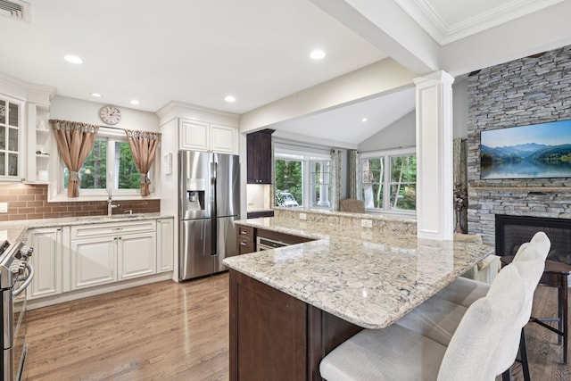 23 Alpine Way S, Huntington, NY 11746 - kitchen with appliances with stainless steel finishes, light stone countertops, light wood-style floors, a kitchen breakfast bar, and vaulted ceiling