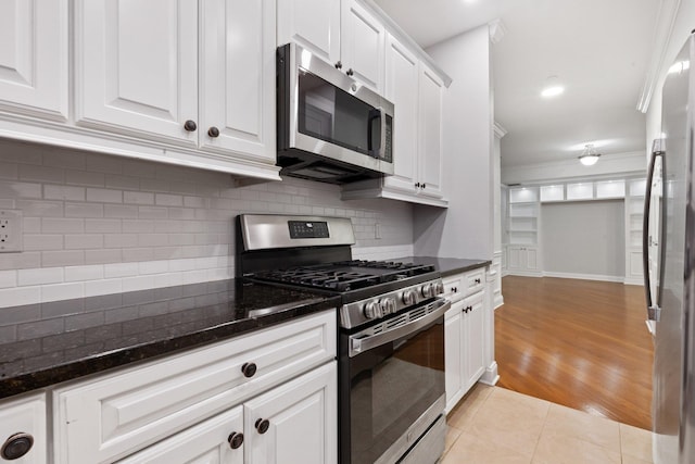 257 Central Ave Unit 1D, White Plains, NY 10606 - kitchen with appliances with stainless steel finishes, crown molding, white cabinetry, backsplash, and light tile patterned floors