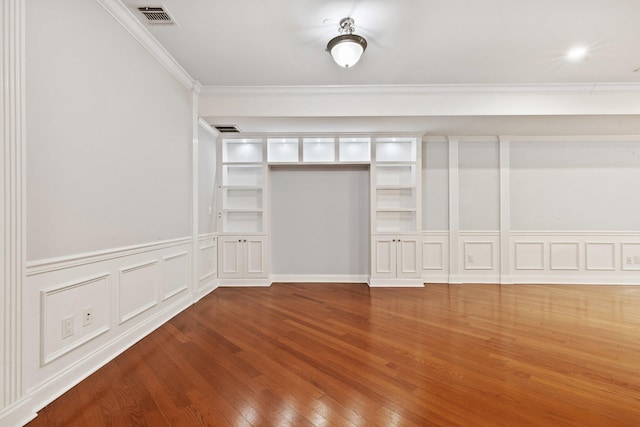 257 Central Ave Unit 1D, White Plains, NY 10606 - unfurnished bedroom featuring crown molding, wood finished floors, a decorative wall, and a wainscoted wall