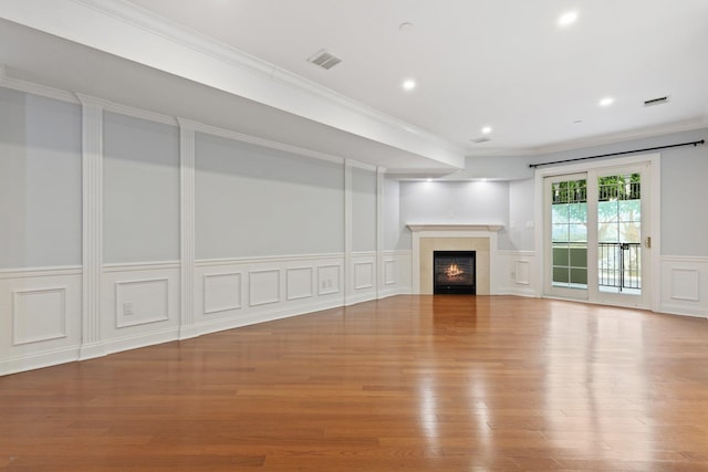 257 Central Ave Unit 1D, White Plains, NY 10606 - unfurnished living room with a decorative wall, wood finished floors, a warm lit fireplace, a wainscoted wall, and ornamental molding