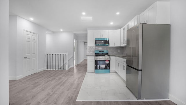 3604 Willett Ave, Bronx, NY 10467 - kitchen featuring stainless steel appliances, white cabinetry, decorative backsplash, recessed lighting, and light wood-style flooring