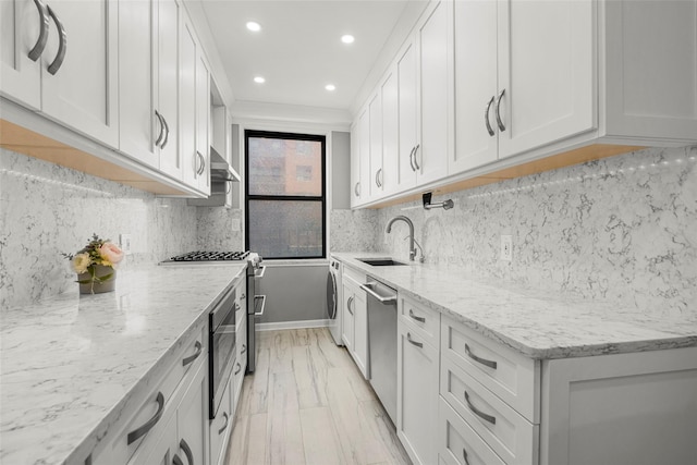 620 W 239th St Unit 2C, Bronx, NY 10463 - kitchen with stainless steel appliances, recessed lighting, washer / clothes dryer, light stone countertops, and wall chimney range hood
