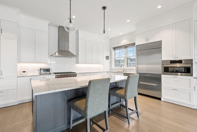720 Davenport Ave Unit 3, New Rochelle, NY 10805 - kitchen featuring appliances with stainless steel finishes, wall chimney range hood, light wood-type flooring, backsplash, and a kitchen island