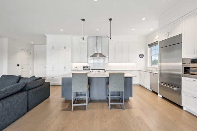 720 Davenport Ave Unit 3, New Rochelle, NY 10805 - kitchen featuring wall chimney range hood, appliances with stainless steel finishes, a breakfast bar area, open floor plan, and light wood-style floors