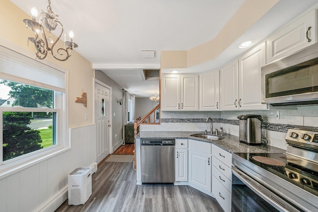 19 Buttercup Ln, Levittown, NY 11756 - kitchen with appliances with stainless steel finishes, a chandelier, white cabinetry, light wood-style flooring, and a wainscoted wall