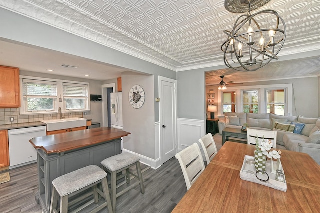 15 5th Ave, Kings Park, NY 11754 - dining room with dark wood-type flooring, a chandelier, an ornate ceiling, a ceiling fan, and a wainscoted wall