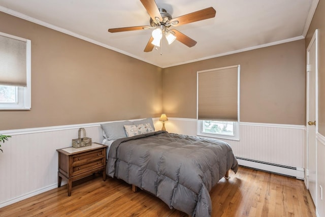 9 Phyllis Ct, Kings Park, NY 11754 - bedroom featuring a baseboard radiator, multiple windows, wood finished floors, a wainscoted wall, and ornamental molding