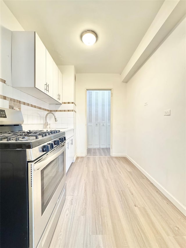 87-10 51st Ave Unit 3E, Elmhurst, NY 11373 - kitchen featuring gas range, light wood finished floors, decorative backsplash, white cabinetry, and light countertops