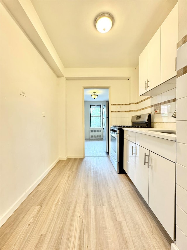 87-10 51st Ave Unit 3E, Elmhurst, NY 11373 - kitchen with stainless steel appliances, light wood-style floors, white cabinetry, light countertops, and radiator