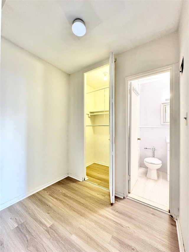 87-10 51st Ave Unit 3E, Elmhurst, NY 11373 - unfurnished bedroom featuring light wood-style flooring, a closet, a walk in closet, and ensuite bathroom