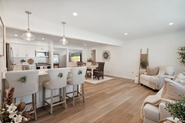 531 Myrtle Ave, West Islip, NY 11795 - kitchen with appliances with stainless steel finishes, open floor plan, a breakfast bar area, light wood-type flooring, and white cabinets