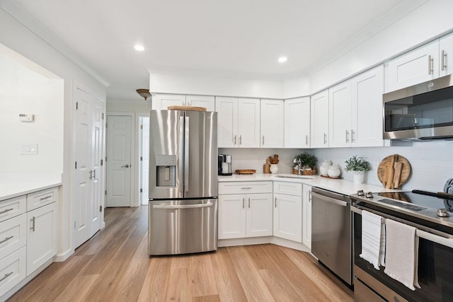 531 Myrtle Ave, West Islip, NY 11795 - kitchen with stainless steel appliances, white cabinetry, light countertops, light wood finished floors, and crown molding