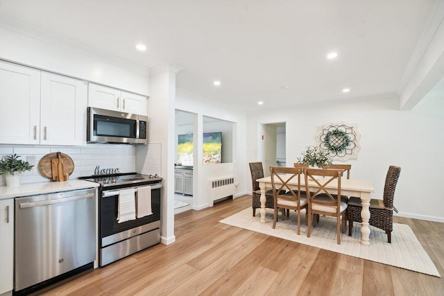 531 Myrtle Ave, West Islip, NY 11795 - kitchen featuring stainless steel appliances, radiator heating unit, white cabinets, decorative backsplash, and crown molding