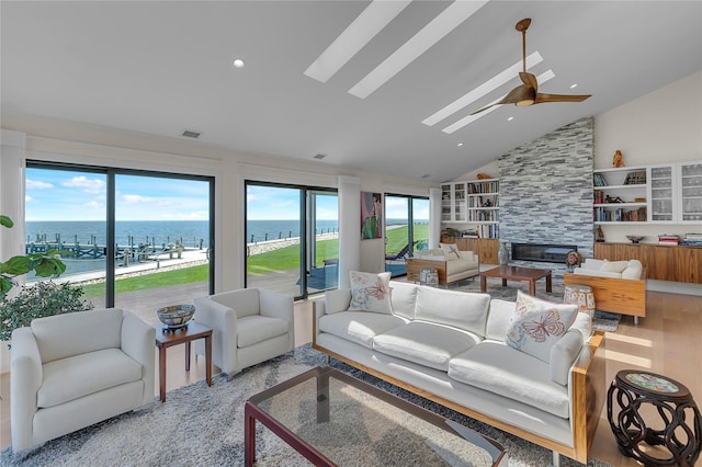 9 Captains Walk E, Bay Shore, NY 11706 - living room featuring a large fireplace, a water view, a ceiling fan, lofted ceiling, and a skylight