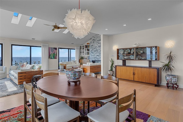 9 Captains Walk E, Bay Shore, NY 11706 - dining area with light wood-style floors, a skylight, vaulted ceiling, recessed lighting, and a stone fireplace
