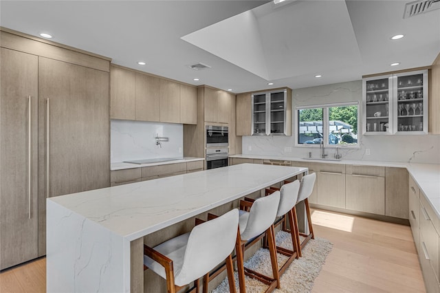 9 Captains Walk E, Bay Shore, NY 11706 - kitchen featuring light wood-type flooring, a kitchen island, light stone counters, backsplash, and recessed lighting