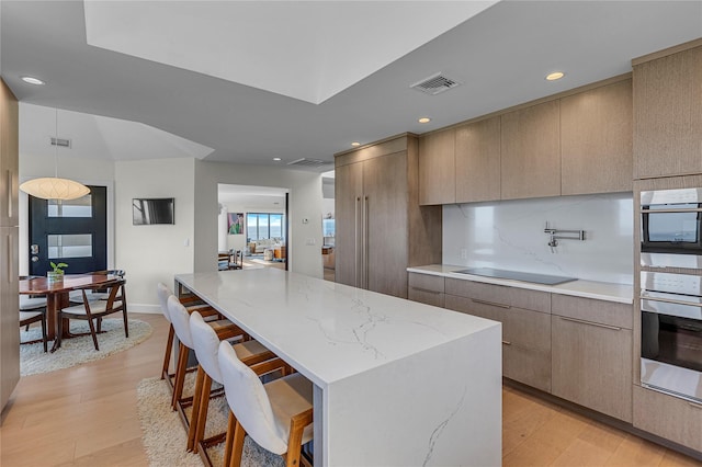 9 Captains Walk E, Bay Shore, NY 11706 - kitchen featuring modern cabinets, light wood finished floors, a kitchen bar, light stone countertops, and a spacious island