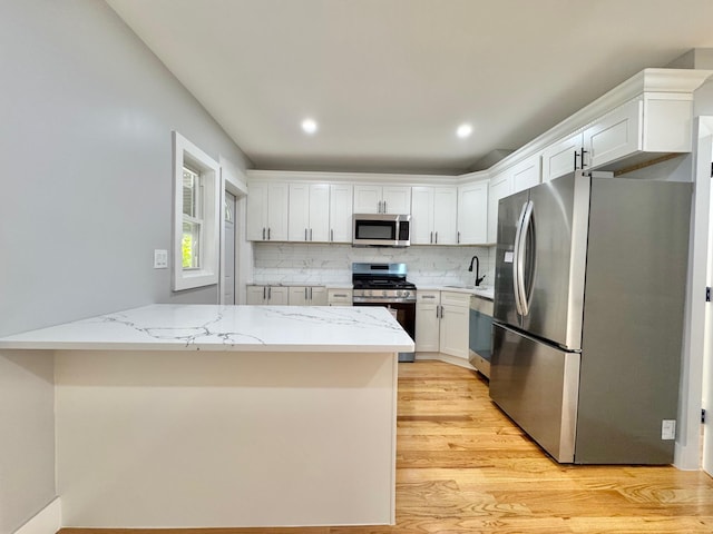 114-62 203rd St, Saint Albans, NY 11412 - kitchen featuring stainless steel appliances, light wood-type flooring, white cabinets, decorative backsplash, and light stone countertops