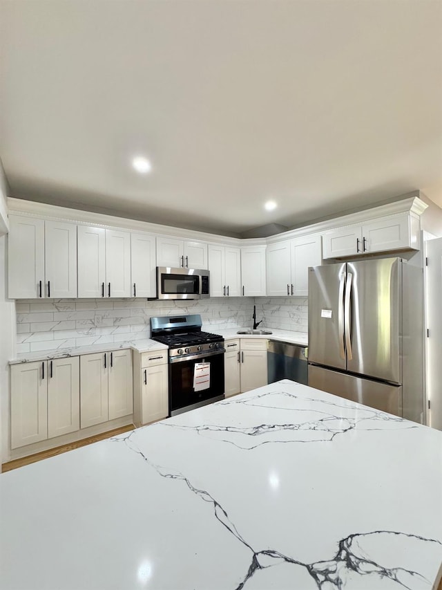 114-62 203rd St, Saint Albans, NY 11412 - kitchen with stainless steel appliances, backsplash, light stone counters, white cabinetry, and recessed lighting
